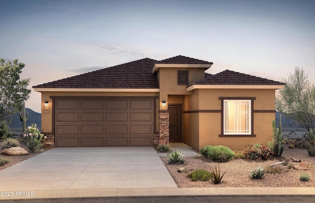 prairie-style home featuring driveway, stone siding, an attached garage, and stucco siding