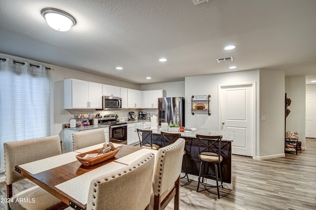 dining room featuring light hardwood / wood-style flooring and a textured ceiling