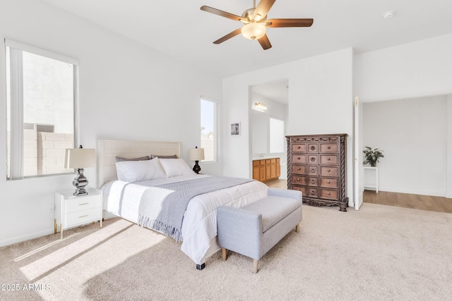 bedroom featuring light colored carpet, ceiling fan, and ensuite bath