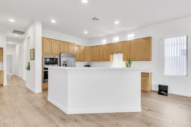 kitchen with a kitchen island, appliances with stainless steel finishes, and light hardwood / wood-style floors