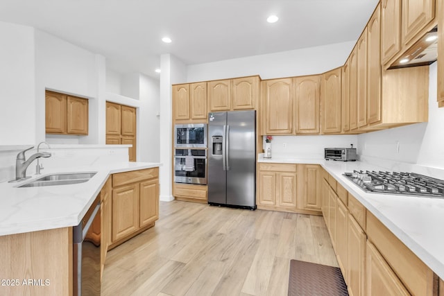 kitchen featuring premium range hood, appliances with stainless steel finishes, light brown cabinetry, sink, and light hardwood / wood-style flooring