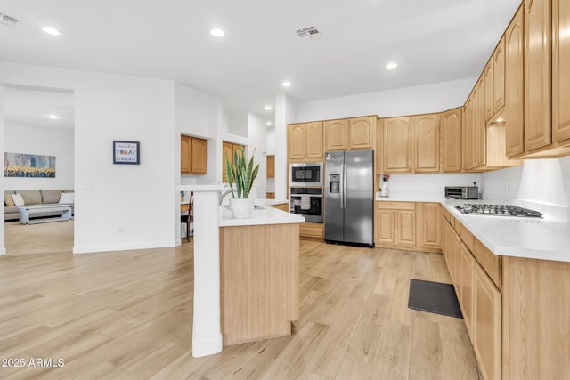 kitchen featuring a kitchen island, appliances with stainless steel finishes, light brown cabinets, and light hardwood / wood-style floors