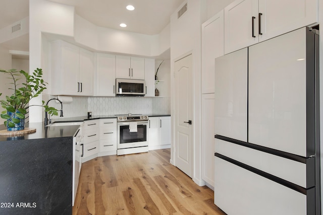 kitchen with backsplash, appliances with stainless steel finishes, sink, light hardwood / wood-style floors, and white cabinets