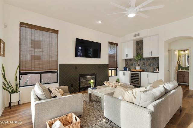 living room with beverage cooler, hardwood / wood-style floors, a tile fireplace, and ceiling fan