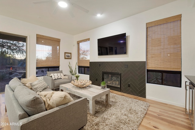 living room featuring light hardwood / wood-style flooring, ceiling fan, and a fireplace