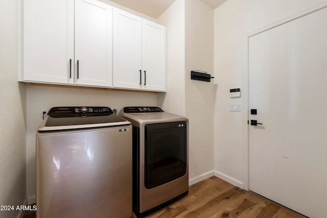 clothes washing area featuring cabinets, separate washer and dryer, and light wood-type flooring