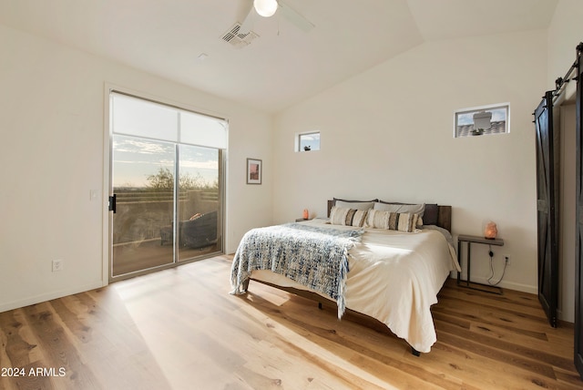 bedroom featuring a barn door, hardwood / wood-style flooring, ceiling fan, and access to exterior