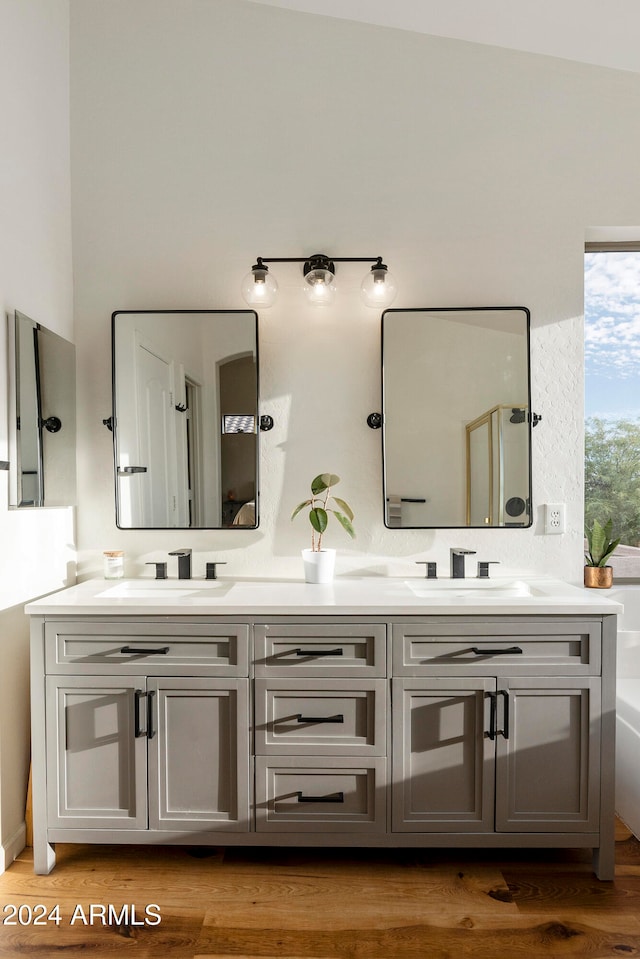 bathroom featuring hardwood / wood-style flooring, a tub to relax in, vanity, and vaulted ceiling