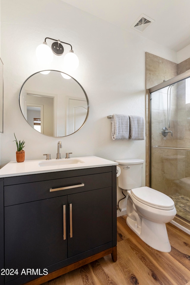 bathroom with hardwood / wood-style floors, an enclosed shower, vanity, and toilet