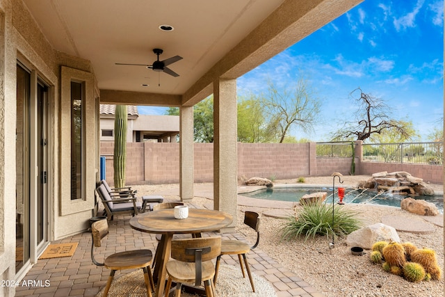 view of patio / terrace featuring ceiling fan, a swimming pool with hot tub, and pool water feature