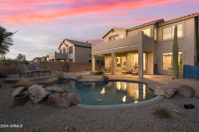 pool at dusk featuring a patio