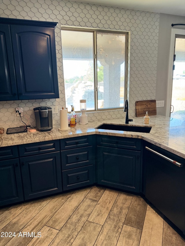 kitchen featuring blue cabinetry, tasteful backsplash, dishwashing machine, and sink