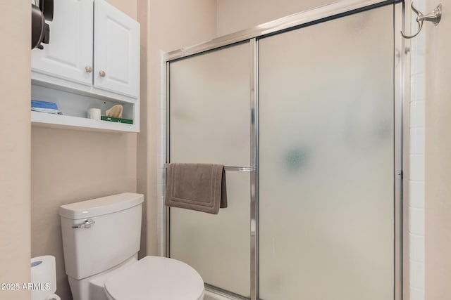 bathroom featuring a shower with shower door and toilet