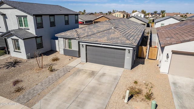 view of front facade with an attached garage, fence, concrete driveway, a residential view, and stucco siding