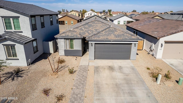 view of front facade with a tile roof, stucco siding, a garage, a residential view, and driveway