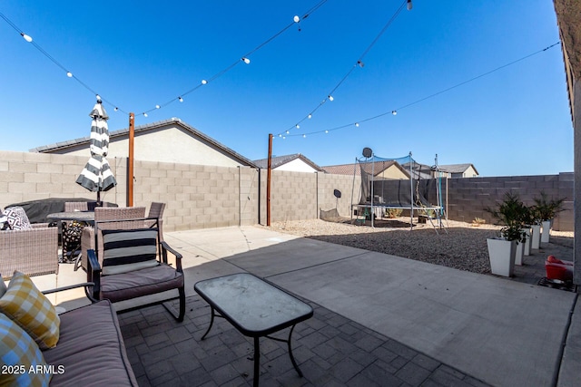 view of patio / terrace featuring a trampoline, outdoor dining area, and a fenced backyard