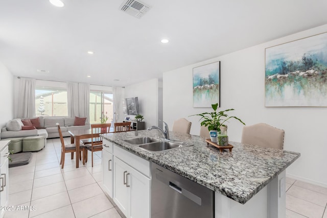 kitchen featuring white cabinets, open floor plan, a kitchen island with sink, stainless steel dishwasher, and a sink