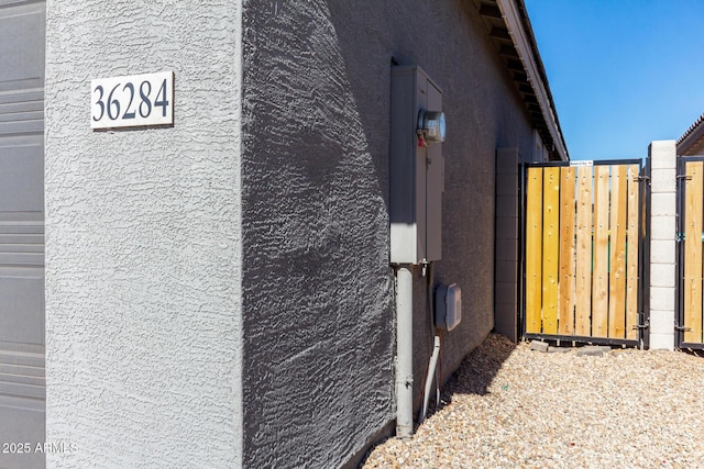 view of side of home featuring a gate and stucco siding