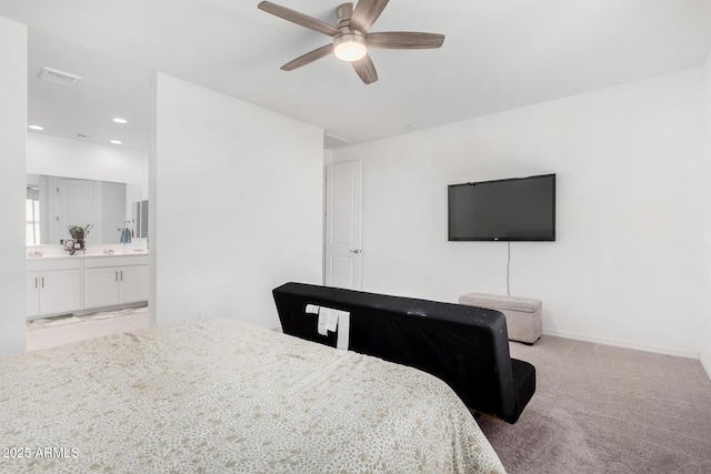 bedroom featuring visible vents, baseboards, light colored carpet, ensuite bath, and ceiling fan