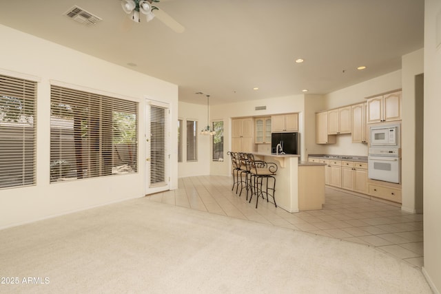 6917 E Night Glow Cir, Scottsdale, AZ 85266 - kitchen featuring white appliances, a kitchen breakfast bar, light brown cabinets, light tile patterned floors, and a ceiling fan