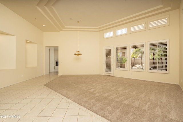 6917 E Night Glow Cir, Scottsdale, AZ 85266 - spare room with a towering ceiling, a tray ceiling, light tile patterned flooring, and light carpet