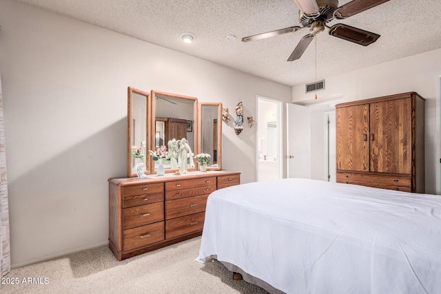 bedroom featuring visible vents, ensuite bath, ceiling fan, a textured ceiling, and light carpet