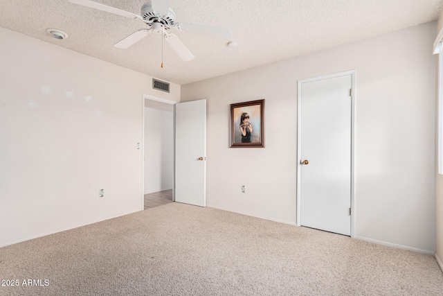 unfurnished bedroom featuring visible vents, light colored carpet, ceiling fan, and a textured ceiling