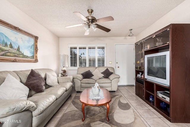 living area with light tile patterned floors, a ceiling fan, and a textured ceiling