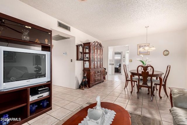 dining area with visible vents, a notable chandelier, light tile patterned flooring, and a textured ceiling