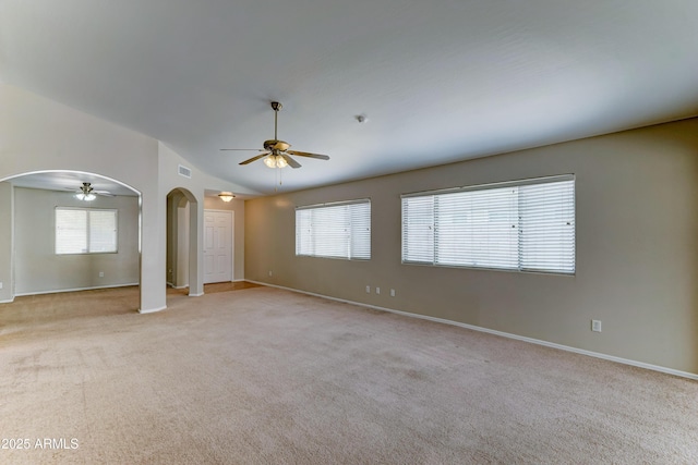 unfurnished room with arched walkways, a ceiling fan, lofted ceiling, and healthy amount of natural light