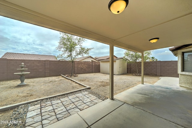 view of patio / terrace featuring a storage unit, a fenced backyard, and an outbuilding