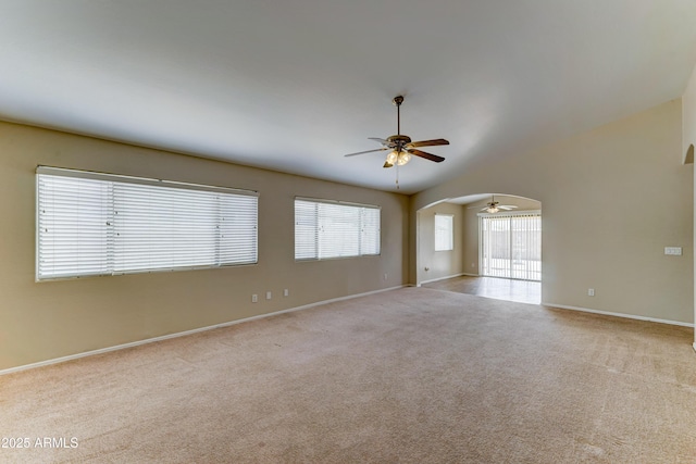 unfurnished room with ceiling fan, carpet, baseboards, and arched walkways