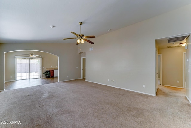 unfurnished living room with arched walkways, ceiling fan, carpet, baseboards, and vaulted ceiling