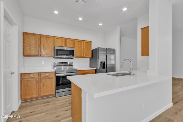 9261 W Sheridan St, Phoenix, AZ 85037 - kitchen with stainless steel appliances, light wood-type flooring, light countertops, a peninsula, and brown cabinets