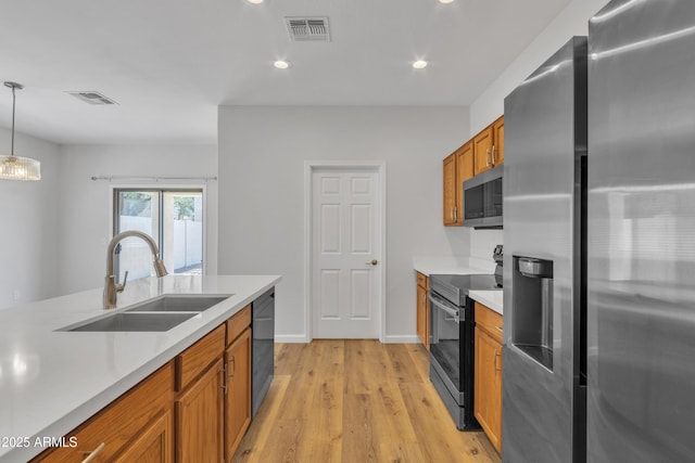 9261 W Sheridan St, Phoenix, AZ 85037 - kitchen featuring stainless steel appliances, brown cabinets, light countertops, light wood-style flooring, and recessed lighting