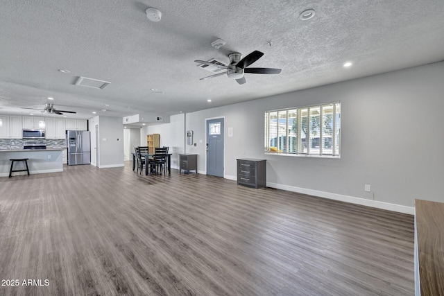 unfurnished living room featuring a textured ceiling, ceiling fan, and dark hardwood / wood-style floors