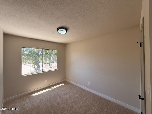 spare room with carpet, baseboards, and a textured ceiling