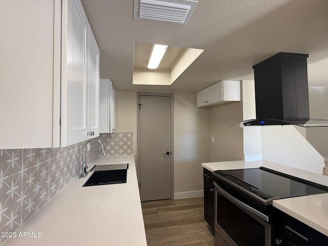 kitchen with stainless steel electric range oven, a sink, white cabinetry, exhaust hood, and light countertops