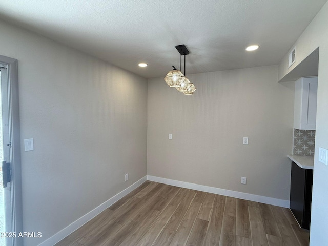 unfurnished dining area featuring wood finished floors, recessed lighting, and baseboards