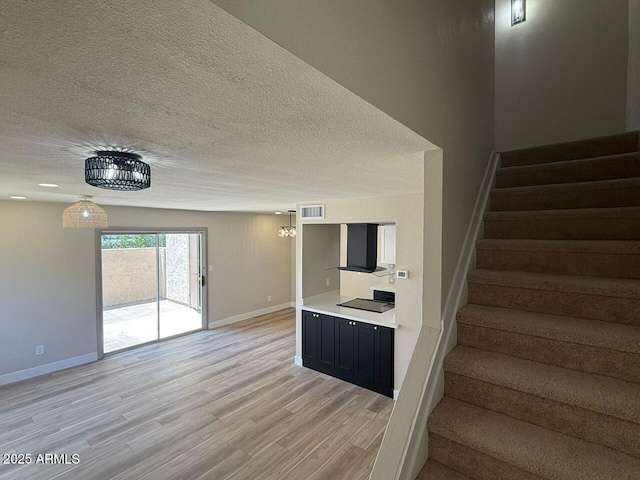 staircase featuring baseboards, wood finished floors, and a textured ceiling