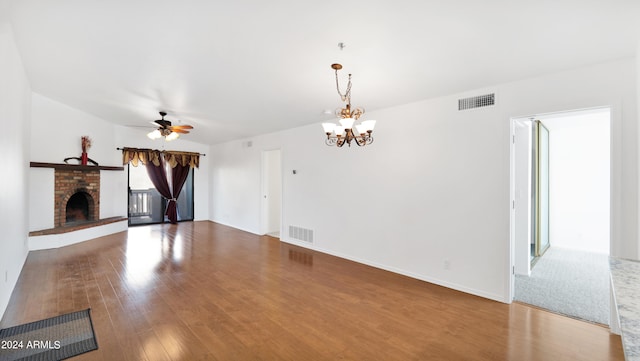 unfurnished living room featuring a brick fireplace, ceiling fan with notable chandelier, and wood-type flooring