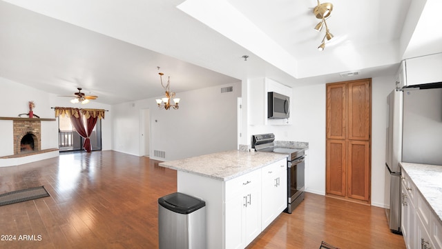 kitchen featuring white cabinetry, stainless steel appliances, light stone countertops, a fireplace, and ceiling fan with notable chandelier