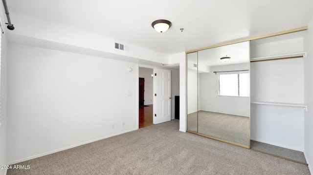 unfurnished bedroom with a closet and light carpet