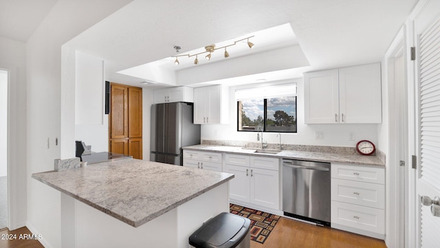 kitchen with white cabinetry, kitchen peninsula, appliances with stainless steel finishes, and light stone countertops