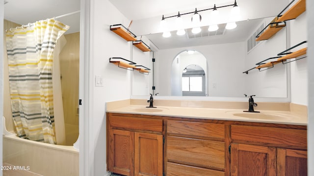 bathroom featuring shower / bath combo, double sink, and vanity with extensive cabinet space