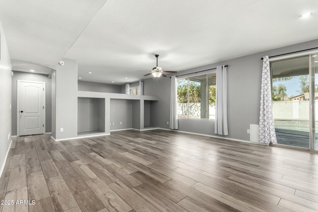 unfurnished living room featuring recessed lighting, wood finished floors, a ceiling fan, and baseboards