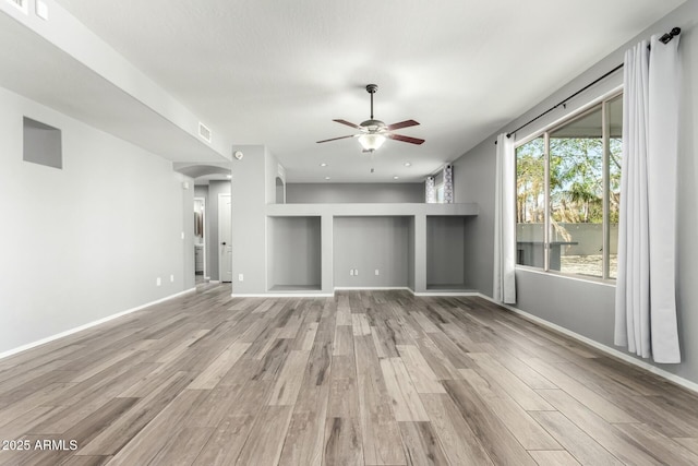 unfurnished living room featuring light wood-type flooring, ceiling fan, visible vents, and baseboards