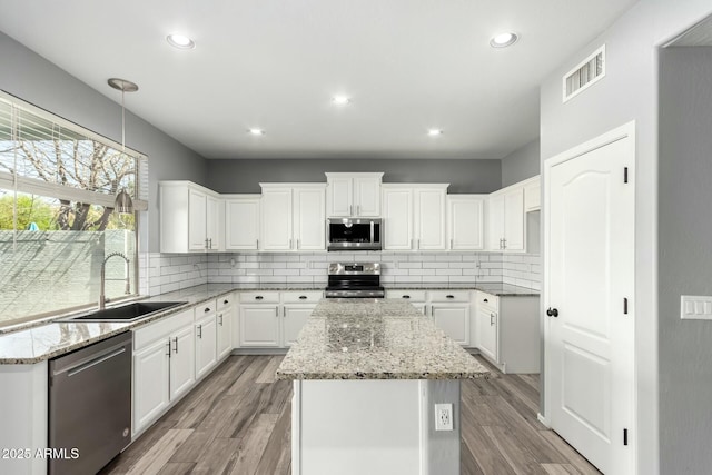 kitchen featuring light wood finished floors, appliances with stainless steel finishes, a sink, and visible vents