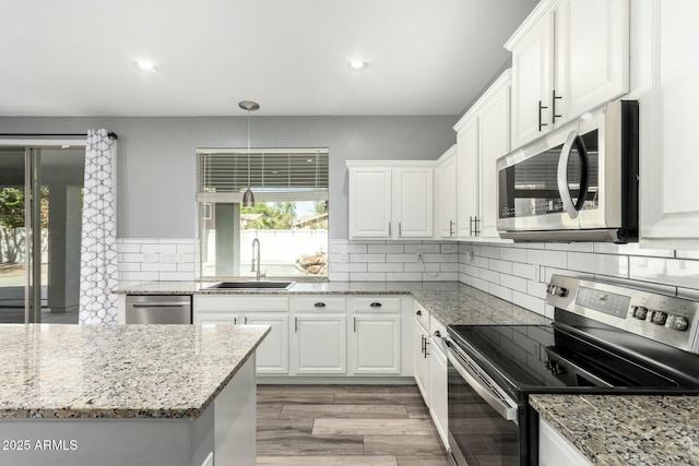 kitchen with appliances with stainless steel finishes, white cabinetry, a sink, and decorative backsplash