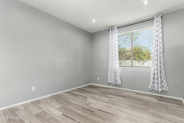 spare room with recessed lighting, baseboards, and light wood finished floors